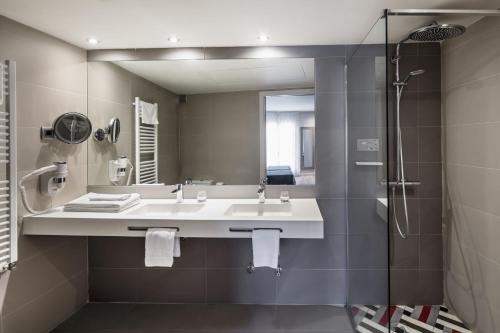 a bathroom with a sink and a shower and a mirror at Balneari Termes Victòria in Caldes de Montbui