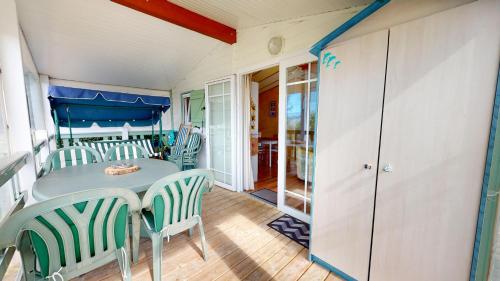 una sala da pranzo con tavolo e sedie su un portico di Mobil Home 40 avec piscines a Brem-sur-Mer