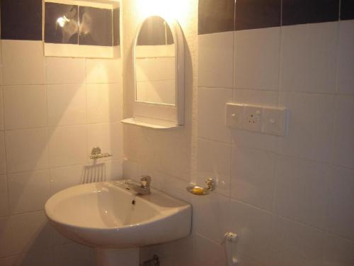 a white bathroom with a sink and a mirror at Kandy River Breeze in Kandy