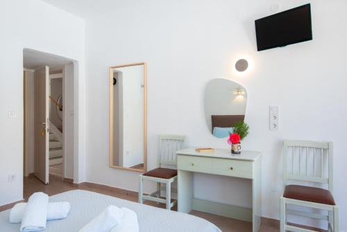 a white bedroom with a desk and a mirror at Simeon Rooms & Apartments in Kamares