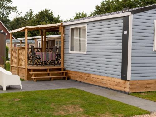 ein blaues Haus mit einer Terrasse und einem Pavillon in der Unterkunft Comfortable chalet with microwave on a holiday park 1 km from the beach in Koudekerke
