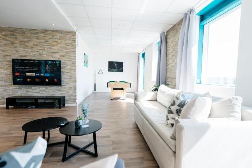 ein Wohnzimmer mit einem weißen Sofa und einer Ziegelwand in der Unterkunft koCASA-Apartments, Penthouse, Panorama, Dachterrasse, zwei Stellplätze, Wifi, Waipu-Tv, Billard in Karlsruhe