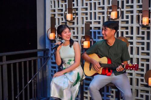 a man and a woman holding a guitar and a microphone at Anantara Vacation Club Mai Khao Phuket in Mai Khao Beach