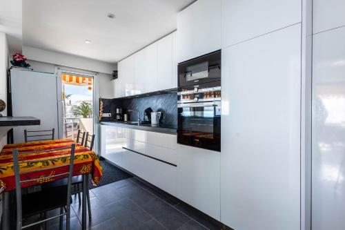 - une cuisine avec des placards blancs et une table à manger dans l'établissement Appartement les pieds dans l'eau pour 6 personnes à Saint-Raphaël, à Saint-Raphaël