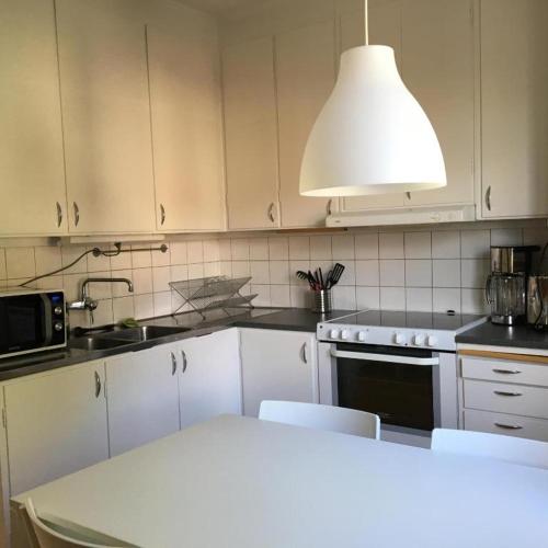 una cucina con armadi bianchi, tavolo e luce di Basement Lounge a Halmstad
