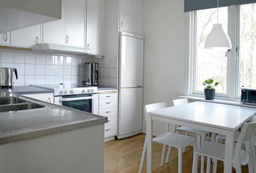 a white kitchen with a table and white appliances at Basement Lounge in Halmstad