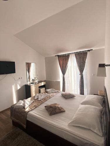 - une chambre avec un grand lit blanc et des rideaux dans l'établissement Pensiunea Antonio, à Pietrari