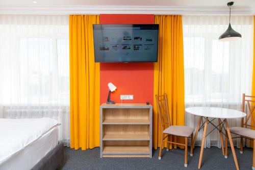a bedroom with orange curtains and a bed and a table at Отель KOKSHETAU in Kokshetau