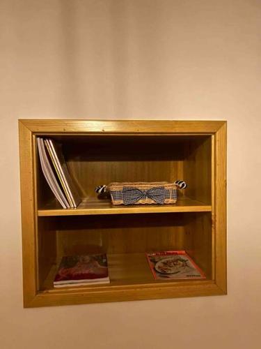 a wooden book shelf with books and a bow tie at Florija’s Guesthouse in Dardhë