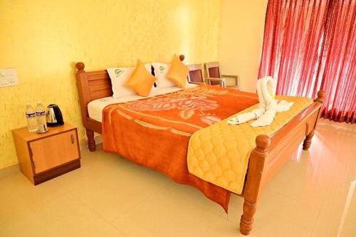 um quarto com uma cama grande e um cobertor laranja em Hotel Misty INN em Yercaud