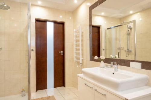 bagno con lavandino, doccia e specchio di Apartament Eliza w centrum APARTZAKOP a Zakopane