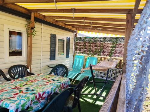 une terrasse couverte avec une table et des chaises. dans l'établissement Mobilhome au camping Les Salins de La Gardiole ex Camping Europe, à Vic-la-Gardiole