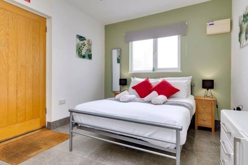 ein Schlafzimmer mit einem großen weißen Bett mit roten Kissen in der Unterkunft Pass the Keys Central Modern Cabin on Mill Road in Cambridge