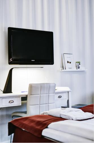 a room with a tv on a wall with a chair at Stadshotellet Kristianstad in Kristianstad