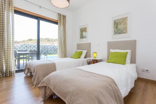 twee bedden in een kamer met een groot raam bij Villa Nooma in Carrapateira