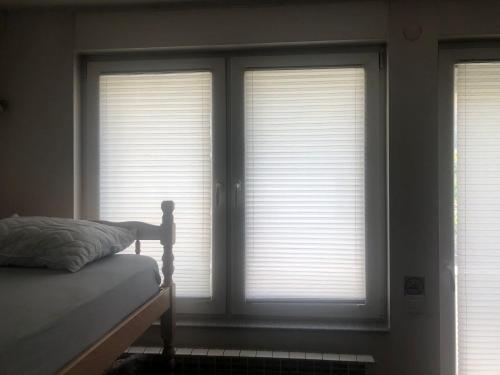 a bedroom with three windows with blinds at Alpi Hostel in Skopje