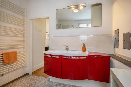 czerwona łazienka z umywalką i lustrem w obiekcie Ferienwohnungen Spiegel Felsgässele w mieście Lindau