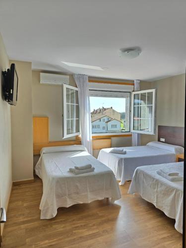 um quarto com duas camas e uma grande janela em Pensión Pedrouzo em O Pedrouzo