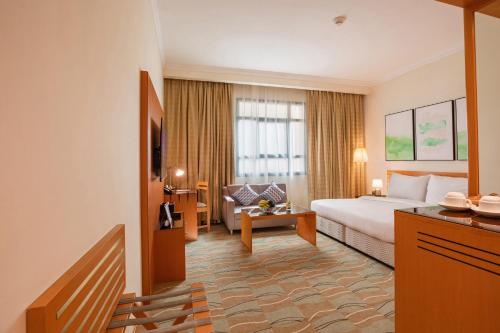 um quarto de hotel com uma cama e uma sala de estar em Swiss-Belinn Doha em Doha
