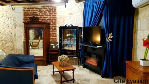 sala de estar con chimenea y cortina azul en Évasion ACCES PMR en Les Roches-lʼÉvêque