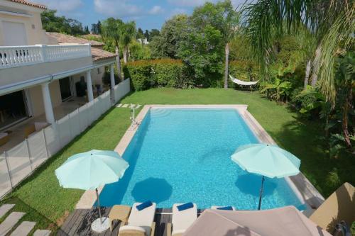 uma piscina com cadeiras e guarda-sóis num quintal em Stunning private Villa with Pool in Antibes em Antibes