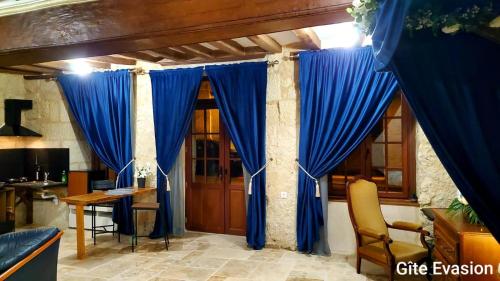Habitación con cortinas azules, mesa y escritorio. en Évasion ACCES PMR en Les Roches-lʼÉvêque