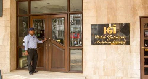 HOTEL GULSHAN INTERNATIONAL في كولْكاتا: رجل واقف امام مبنى