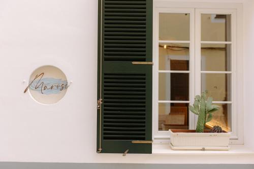 ein Fenster mit einem grünen Rollladen neben einem Kaktus in der Unterkunft Marosi Boutique Hotel in Ciutadella