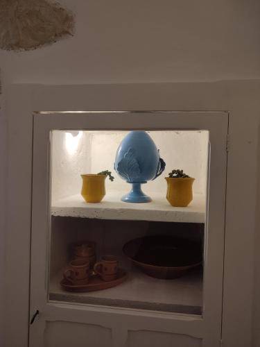 a shelf with a blue vase and some cups at Dimora Ludovica in Copertino