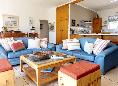 una sala de estar con 2 sofás azules y una mesa. en Beach Haven Cottage, en Britannia Bay