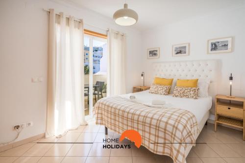 um quarto branco com uma cama e uma janela em #001 Cosy flat in Old Town near beach em Albufeira