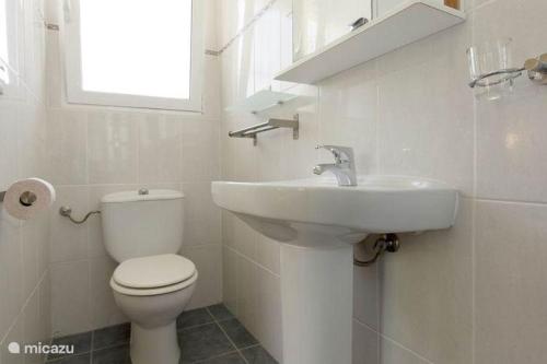 a white bathroom with a toilet and a sink at Residence Bougainville in La Nucía