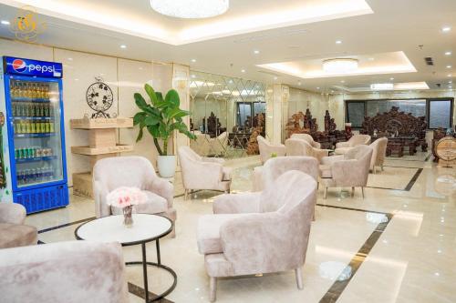 una sala de espera con sillas, mesas y un reloj en Glory Hotel Apartment Hải Phòng, en Hai Phong