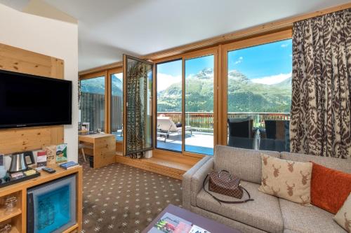 a living room with a couch and a large window at Nira Alpina in Silvaplana