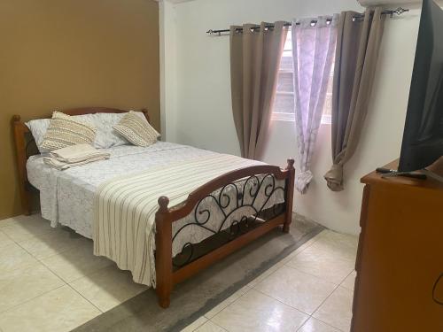 Schlafzimmer mit einem Bett und einem Fenster in der Unterkunft Cozy Quarters Tobago in Scarborough