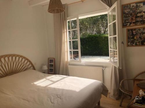 une chambre avec un lit et une grande fenêtre dans l'établissement Villa landaise avec piscine, à Vielle-Saint-Girons