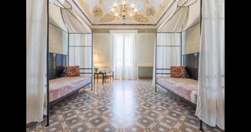 a bedroom with two beds and a chandelier at Palazzo Fasti in Casarano