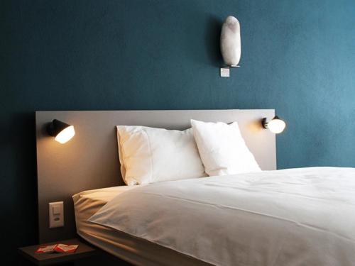 a bedroom with a bed with two lights on the wall at Stockberg hotel & apartments in Siebnen