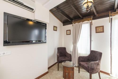 a living room with two chairs and a flat screen tv at Naz Wooden House Inn in Istanbul