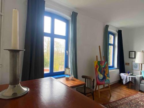een woonkamer met een tafel en 2 ramen bij Vierländer Hippiehof in Hamburg