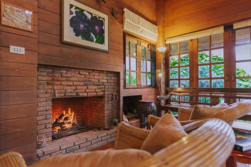 清邁的住宿－Muangkham Cabin，客厅设有壁炉、椅子和沙发