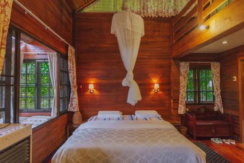 ein Schlafzimmer mit einem Bett in einem Zimmer mit Holzwänden in der Unterkunft Muangkham Cabin in Chiang Mai