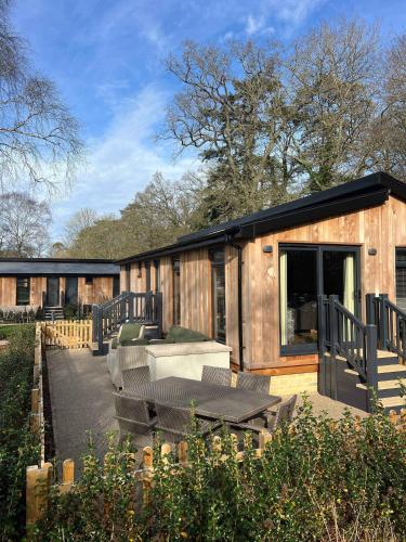 a wooden house with a patio and a table and chairs at Blenheim Palace Lodge Retreat in Woodstock