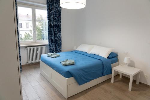 - une chambre avec un lit doté de draps bleus et une fenêtre dans l'établissement Casa Zaffiro, à Savillan