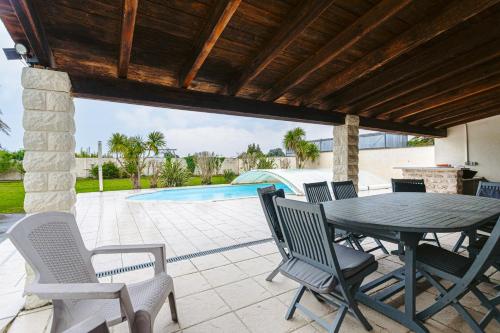 un patio avec une table et des chaises et une piscine dans l'établissement Maison Boyardville Piscine Chauffée, à Saint-Georges-dʼOléron