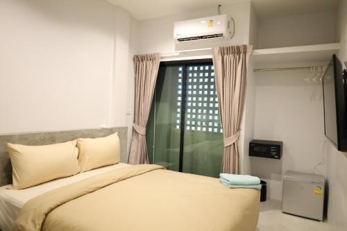 a bedroom with a bed and a window with a television at Y House Patong in Patong Beach