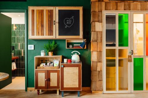 una cocina con paredes verdes y armarios de madera en Treehouse Hotel Manchester, en Mánchester