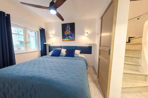 une chambre avec un lit bleu avec un ventilateur de plafond dans l'établissement Maison Mazuc- Central Townhouse Pezenas with Terrace, à Pézenas
