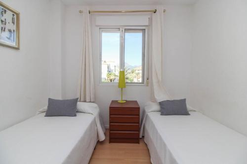 two twin beds in a room with a window at Apartamento Golf Pau Casals in Albir