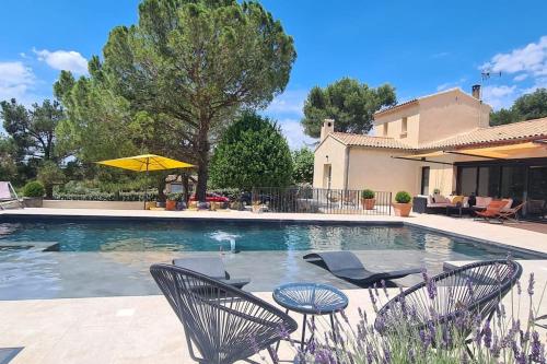 une piscine avec des chaises et un parasol dans l'établissement Thaliana, à Saumane-de-Vaucluse